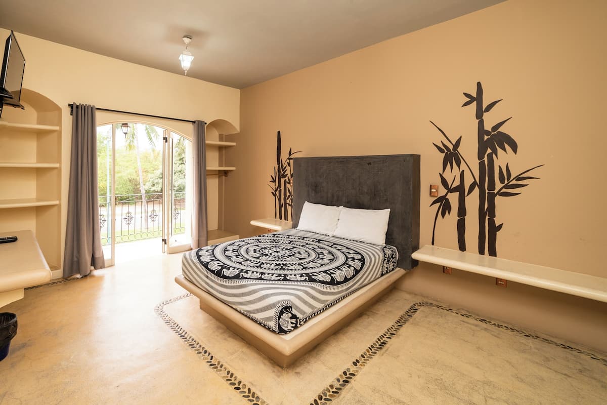 Une chambre à coucher comprenant un lit, une table de chevet, une étagère, une porte et un mur décoré de motifs en bambou.