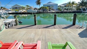 A marina with boats docked, a wooden deck, and a clear blue sky. - Little Island Pearl (Key Colony Beach)