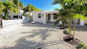 A white building with a gravel driveway and palm trees. - Little Island Pearl (Key Colony Beach)
