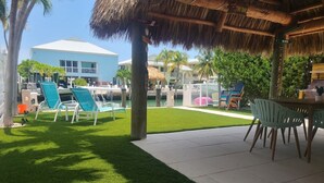 A resort area with a thatched-roof pavilion, outdoor seating, and a pool. - Little Island Pearl (Key Colony Beach)