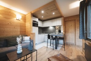 Een modern interieur met een houten wand, een keukenhoek en een zithoek met een bank en een tafel.