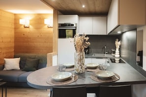 A modern kitchen with a dining area, wooden walls, and a central island with a vase of dried flowers. - A magnificent 34-square-meter apartment for 4 people with a view of the snow-capped mountains (VAL THORENS)