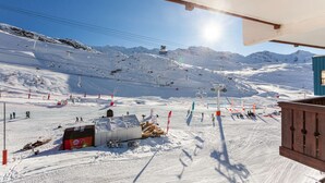 A ski resort with a chairlift, ski slopes, and a building with a blue roof.