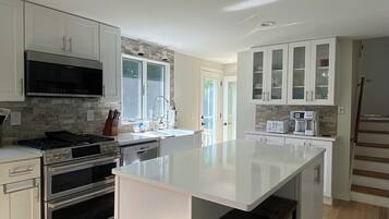 Enjoy cooking in this kitchen with a central island, bar stools, stainless steel appliances, and white cabinetry.