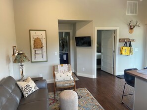 A living room with a sofa, a chair, a lamp, a rug, and a television. - Bozeman Beehive (Bozeman)