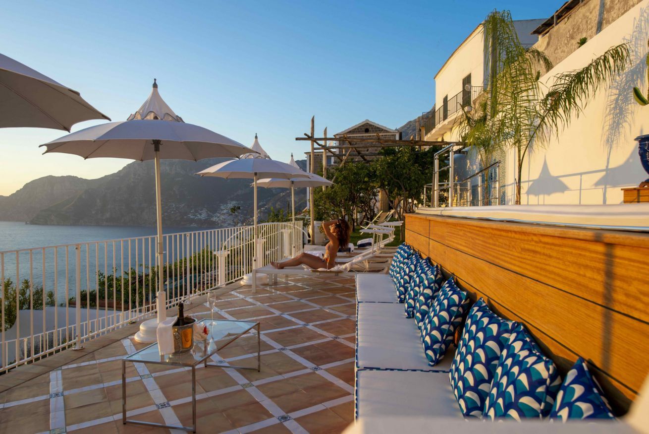A terrace with a view of the sea, outdoor seating, and umbrellas.