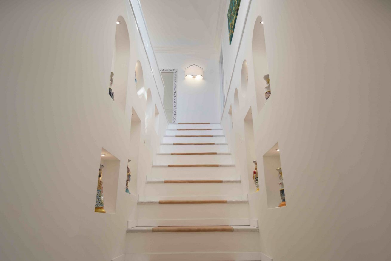 Una scala all'interno di un edificio con pareti bianche e diverse piccole finestre.
