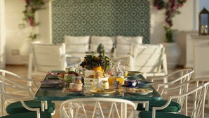 Une table à manger dressée avec des assiettes, des tasses et une carafe de jus d’orange.