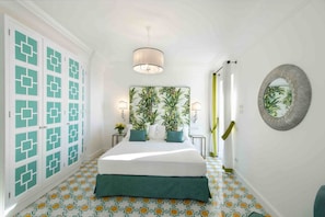 A bedroom with a bed, a nightstand, a wall-mounted mirror, and patterned floor tiles. - MyExclusiveItaly - Exclusive Villa in Praiano with Pool & View (Praiano)