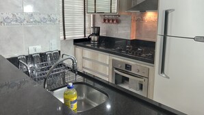Una cocina moderna con un refrigerador de acero inoxidable, una cafetera y un escurreplatos.