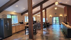Una cocina amplia con una isla central, vigas de madera y un comedor con vistas al exterior.
