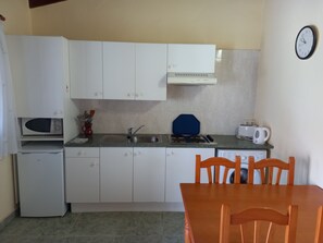Compact kitchen with a stove, sink, and microwave, perfect for preparing meals.