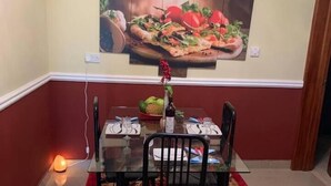 Ein Essbereich mit einem Glastisch, vier Stühlen, einem Teppich mit roten und beigen Mustern sowie einer Wand-Klimaanlage.