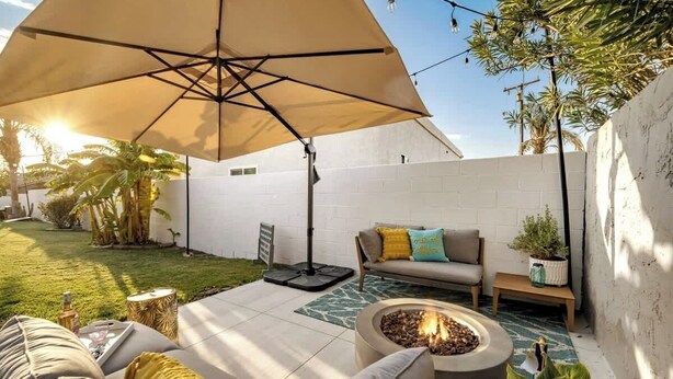 An outdoor patio area with a fire pit, a sofa, and an umbrella.