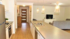 A modern kitchen with stainless steel appliances, a central island with a sink, and pendant lighting.