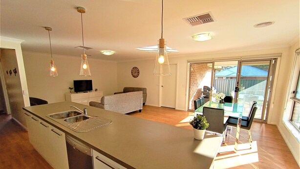 A modern kitchen with a central island, a dining area with a table and chairs, and a living space with a sofa.