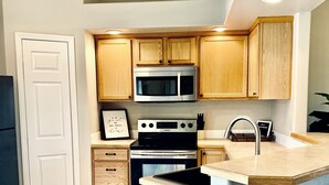 A compact kitchen with wooden cabinets, a built-in microwave, a stove, and a sink. -  Spacious and Cozy with bonus room! (meridian)