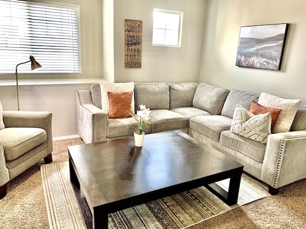 A living room with a sectional sofa, a coffee table, and a lamp.