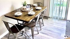 A dining area with a wooden table, metal chairs, a chandelier, a mirror, and a view of the outdoors through large windows. -  Spacious and Cozy with bonus room! (meridian)