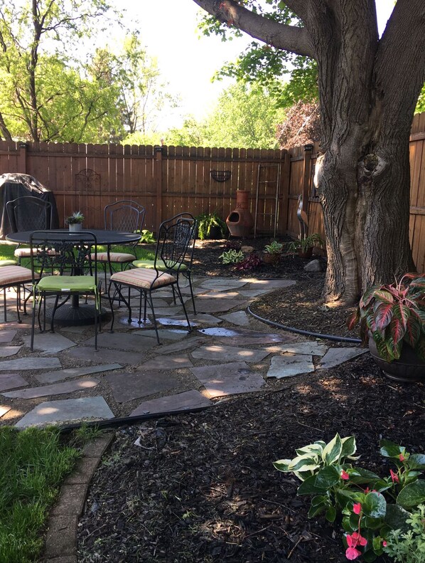 Eine Terrasse mit Tisch und Stühlen, umgeben von einem Holzzaun und einem Baum.