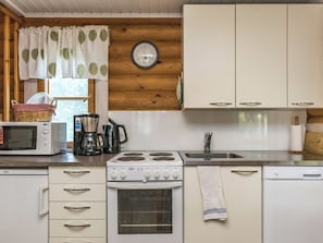 A compact kitchen with a microwave, coffee maker, stove, and sink. - Vihreä mökki by Interhome (Punkaharju)