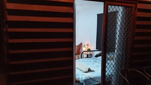 A room with a bed, a chair, and a small table. There is a sliding door with a mesh screen. - Farm Stay Cottage in the beautiful Gold coast hinterland (Illinbah)