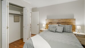 Une chambre à coucher avec un lit, des tables de chevet, une tête de lit en bois et une armoire.