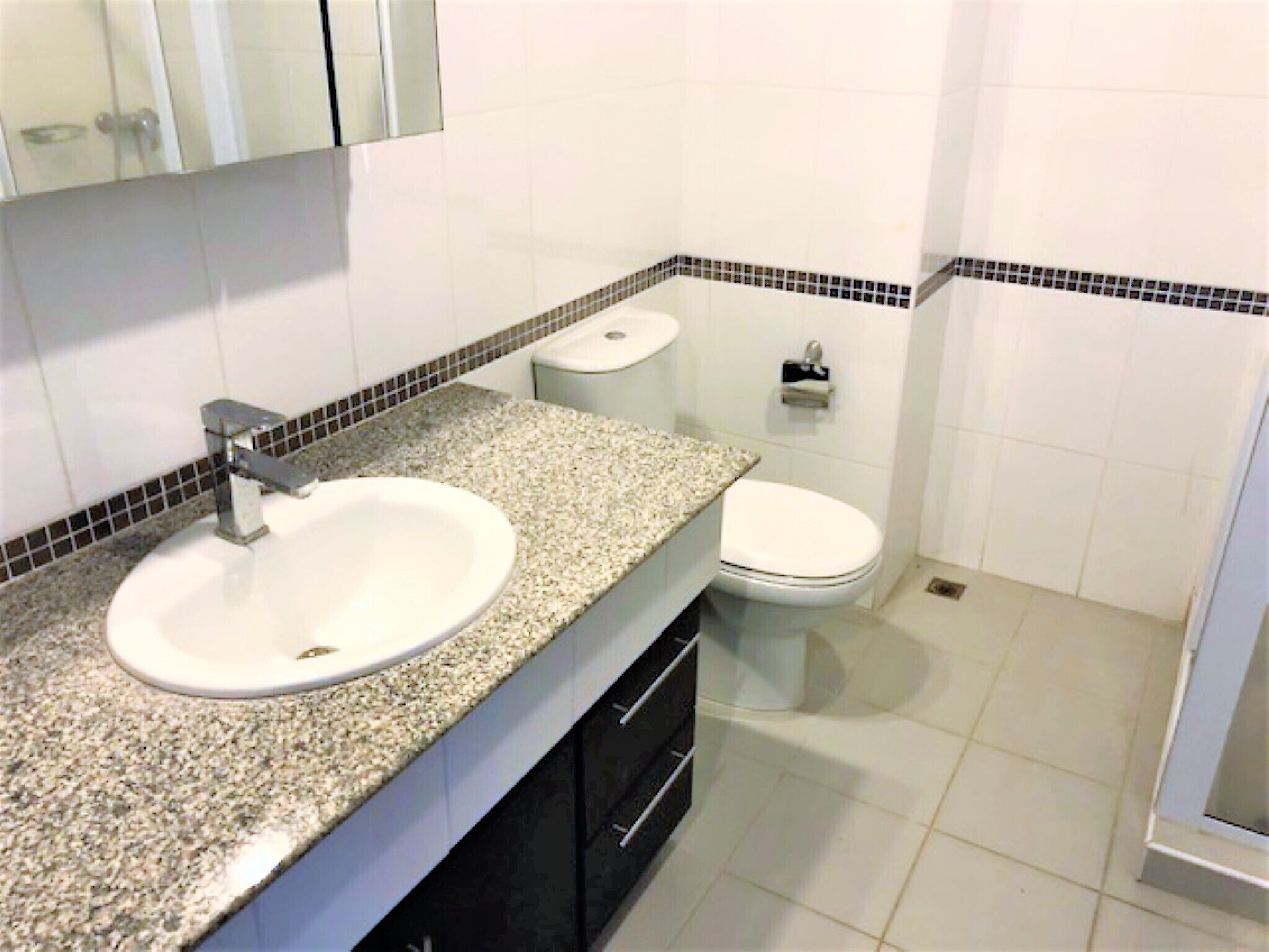 Une salle de bain avec un lavabo à vasque en granit, des toilettes et un miroir au-dessus du lavabo.