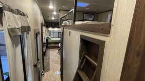 A narrow hallway with a wooden ladder, a bunk bed, and a small kitchenette area. - Spacious Palapa half a block of waterfront. (Loreto)