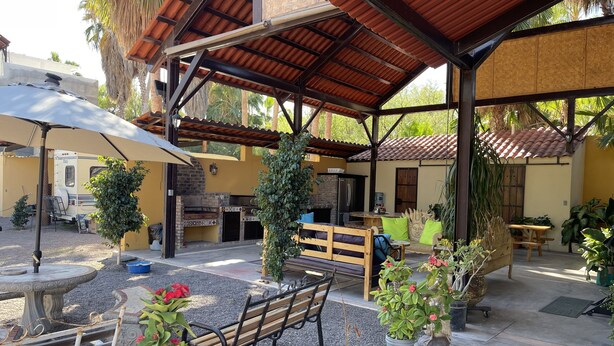 An outdoor patio area with a covered seating area, a barbecue grill, and a dining table. - Spacious Palapa half a block of waterfront. (Loreto)