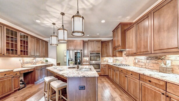 A spacious kitchen with wooden cabinets, a marble countertop, and stainless steel appliances. - 9-bedroom Luxury Home, 4.8 Acre w/ Pool, Minutes to Suwanee downtown and Lake (Suwanee)