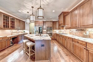 A spacious kitchen with wooden cabinets, a marble countertop, and stainless steel appliances.