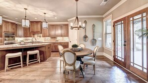 A spacious kitchen with wooden cabinets, a large island, and pendant lighting. - 9-bedroom Luxury Home, 4.8 Acre w/ Pool, Minutes to Suwanee downtown and Lake (Suwanee)