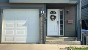 Une maison à deux étages avec un garage, une porte d’entrée ornée d’une guirlande et une antenne parabolique.