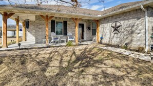 A house with a covered porch, a brick exterior, and a star emblem on the wall. - 'Leaping Toad Ranch' ~ 9 Mi to Lake Granbury! (Granbury)