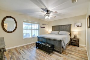 Une chambre à coucher avec un grand lit, un ventilateur de plafond, une fenêtre, un miroir et un banc en bois.