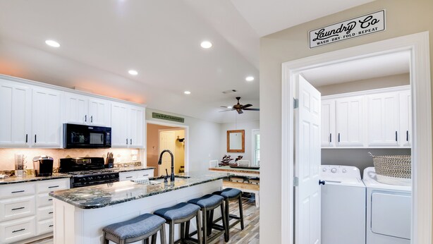 A modern kitchen with white cabinets, a granite countertop, and a built-in island with bar stools. - 'Leaping Toad Ranch' ~ 9 Mi to Lake Granbury! (Granbury)