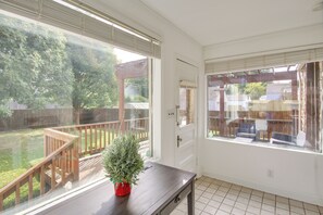 Une pièce avec vue sur un jardin, une terrasse en bois et une plante en pot posée sur une table.