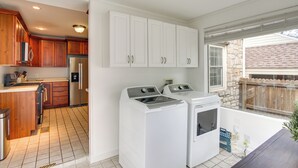 Un cuarto de lavandería con lavadora y secadora, armarios de madera y una zona de cocina con refrigerador.