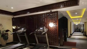 A gym area with treadmills and exercise equipment, wooden paneling, and a hallway leading to other rooms.