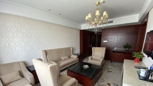 A modern living room with a sofa, armchairs, a coffee table, and a TV.