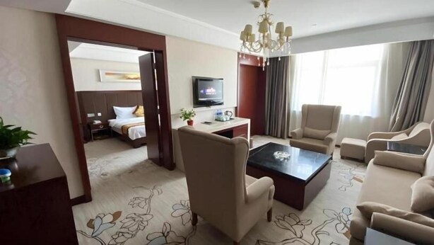 A hotel room with a bed, a TV, a coffee table, and seating area.