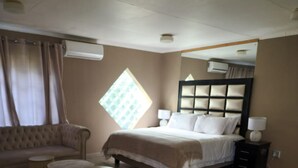 Een slaapkamer met een bed, een bank, twee ronde tafels en een groot raam.