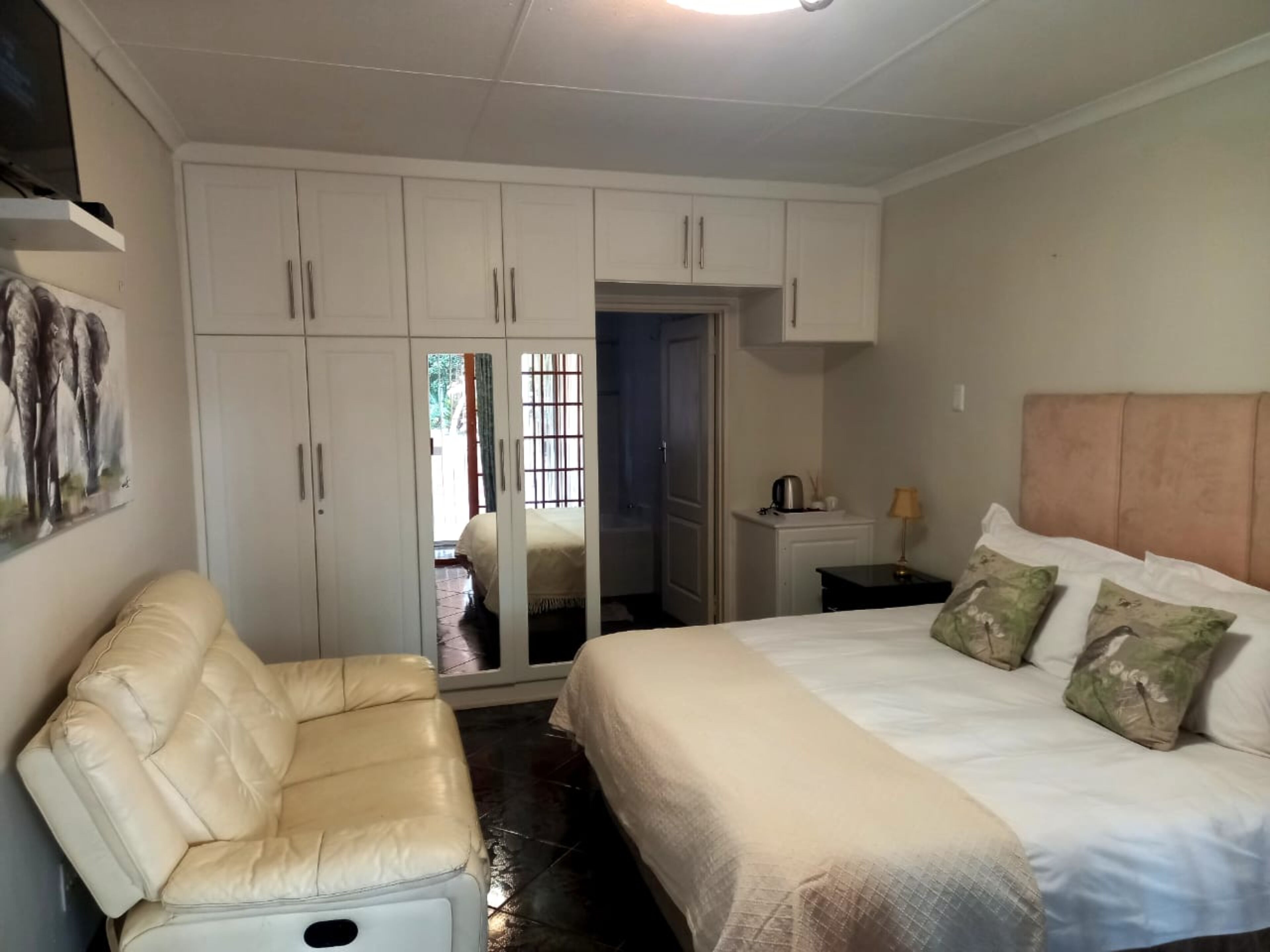 A bedroom with a bed, a chair, a wardrobe, and a nightstand.