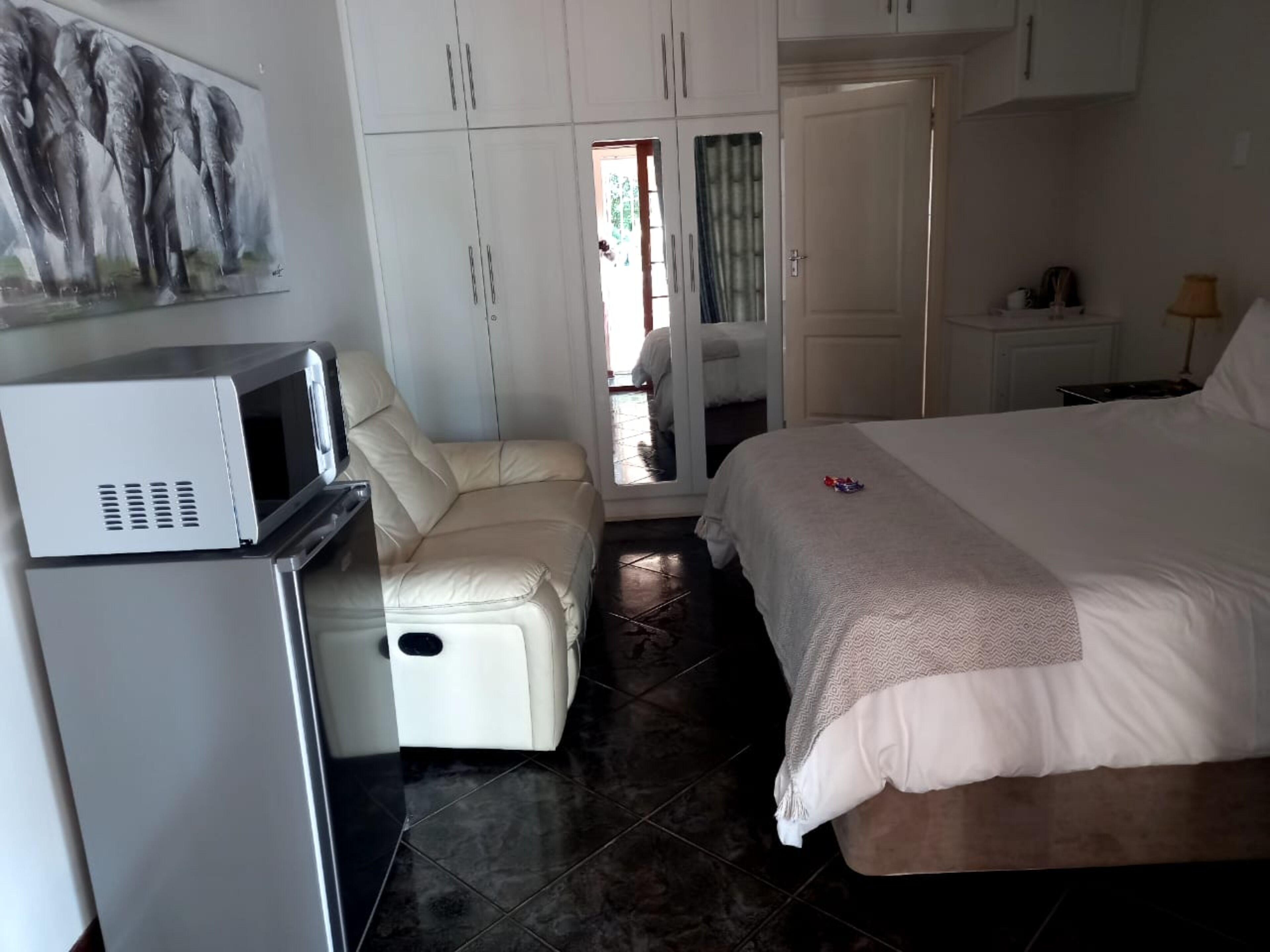 A bedroom with a bed, a sofa, a microwave, and a wardrobe.