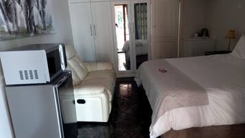A bedroom with a bed, a sofa, a microwave, and a wardrobe.