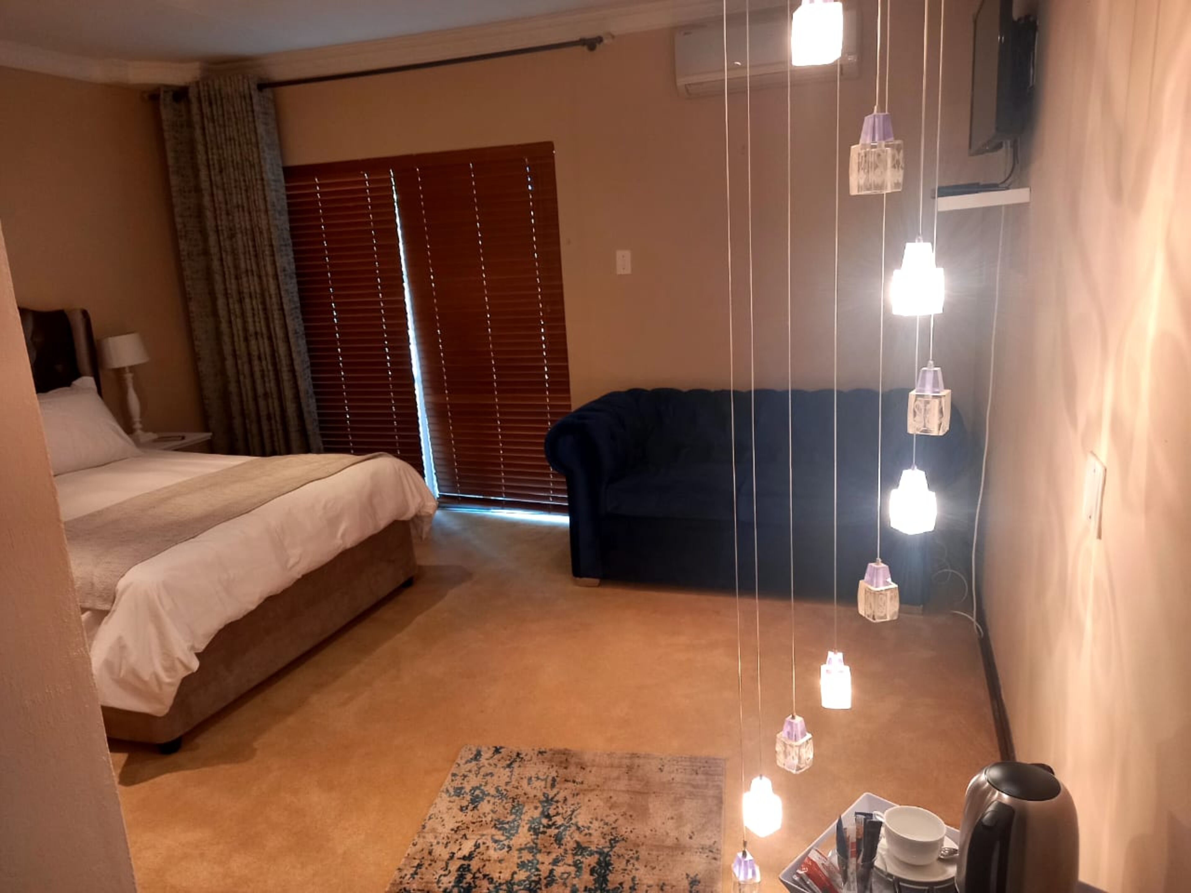 Una habitación de hotel con cama, sofá, mesa de centro e iluminación colgante.