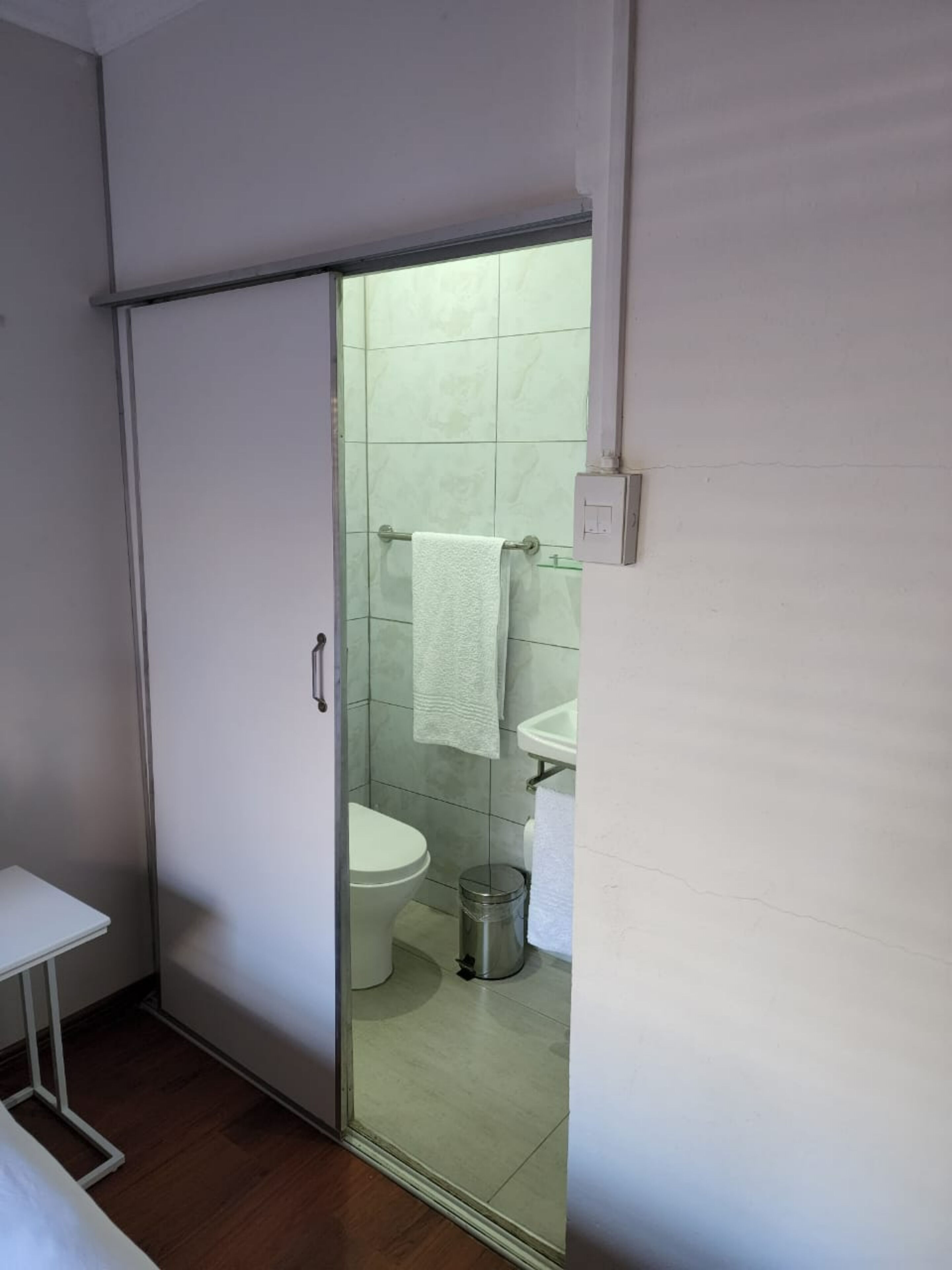 A bathroom with a toilet, a sink, and a trash bin.