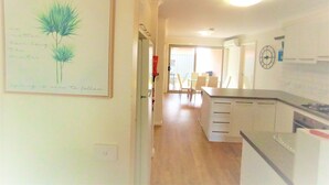 A kitchen with a dining area, a staircase, and a hallway with a framed artwork.