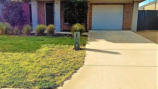A residential house with a garage, a well-maintained lawn, and a mailbox.